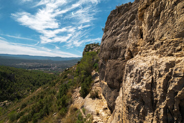 landscape of Rocky Cliffside Path Overlooking Lush Green Valley with Expansive Sky View