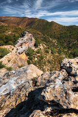 landscape of Rocky Cliffside Path Overlooking Lush Green Valley with Expansive Sky View