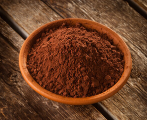 Bowl of cocoa powder sitting on rustic wooden table