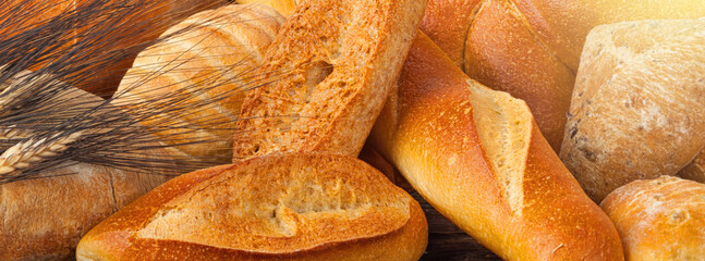 Freshly baked bread and wheat stalks forming a bread background