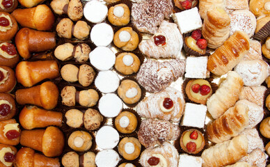 Variety of delicious sweet pastries arranged in rows on a table