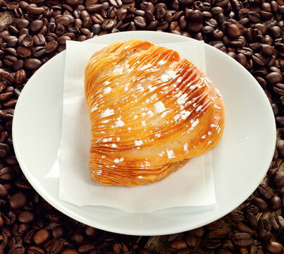 Delicious sfogliatella lying on plate with coffee beans