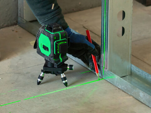 Construction worker using a cross line laser level during finishing work