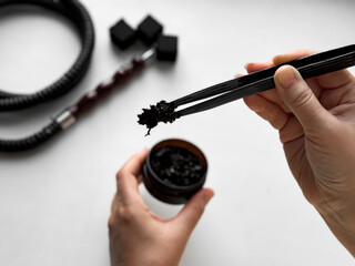 Hands preparing hookah, close up of charcoal and tobacco setup