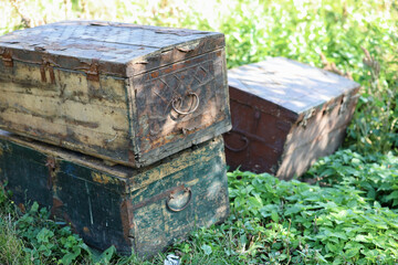 Three old wood chests closed outdoor on green grass.