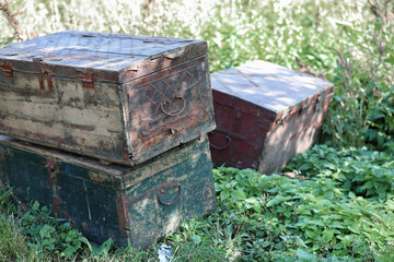 Three old wood chests closed outdoor on green grass. Side view.