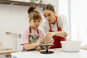 Mother and daughter create pottery together in a bright studio