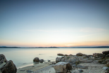 View through rocks on a sandy beach into the sunset. Landscape shot with a view to the horizon over...