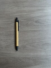 Recycled cardboard pen on a gray wooden table. Vertical photo of a pen on the table with copyspace to the right. Business concept. Shot Of School Supplies, simple concept.
