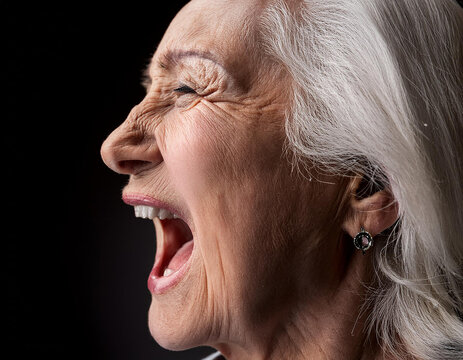 mujer mayor gritando con expresi&oacute;n fuerte sobre fondo negro, concepto de emociones humanas, ira, frustraci&oacute;n, enfado, estr&eacute;s o grito de liberaci&oacute;n emocional