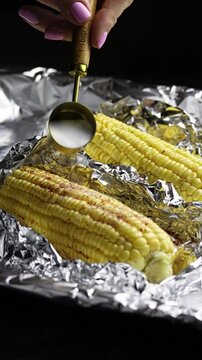Cooking corn. Preparing corn for baking. Adding salt to corn to bake it. Fresh cron cobs being salted to roast in the oven, slow motion