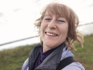 A cheerful woman blogger enjoying a leisurely stroll along the scenic coastal path on a beautiful day