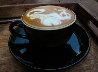 Close up black coffee cup with latte art on wood tab