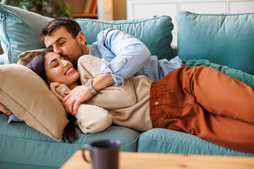 Obraz premium Couple cuddling and kissing while relaxing at home