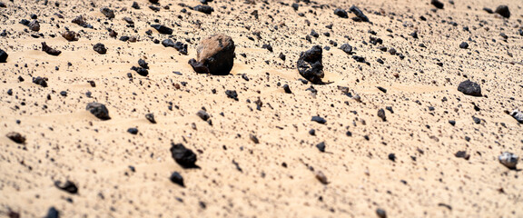 A sandy terrain with stones closeup in a daylight.