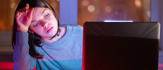 Girl works on a laptop at home at night.