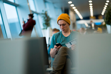 Man is sitting at the airport, waiting for flight.