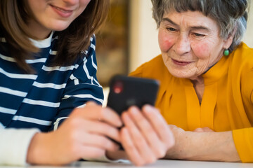 Girl helps her grandmother with mobile phone.
