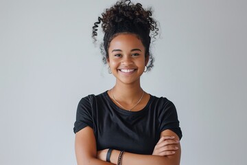 Portrait of a young woman with a genuine smile and arms folded, against a white background , background blur