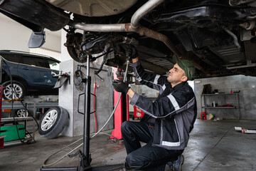 A skilled mechanic is working under a vehicle in an auto repair shop, performing maintenance. The scene conveys a sense of professionalism and attention to detail in car repair work.