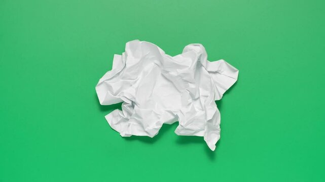 Stop motion animation of crumpled pape on a green background.