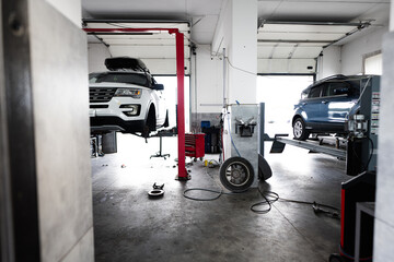 Interior of a modern auto repair shop featuring vehicles on hydraulic lifts. The spacious garage is...