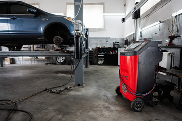 Fototapeta premium Image of a modern auto repair garage featuring a vehicle on a hydraulic lift and advanced equipment for maintenance services. Provides an industrial and technical environment for automotive work.