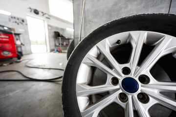 Detailed close-up of a car wheel and tire in a modern automotive workshop, highlighting the craftsmanship and industrial setting.