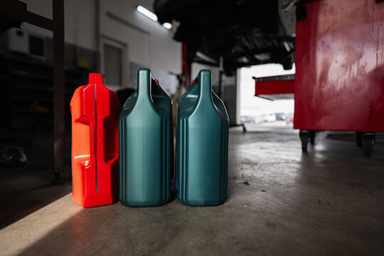 Colorful plastic containers are placed on the floor in an automotive workshop, highlighting industrial and maintenance themes in a garage environment.