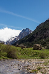 Naklejka premium Scenic Mountain Landscape with Stream and Rustic House Under Clear Blue Sky