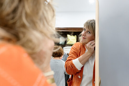 Woman checking her earring in mirror at clothing store