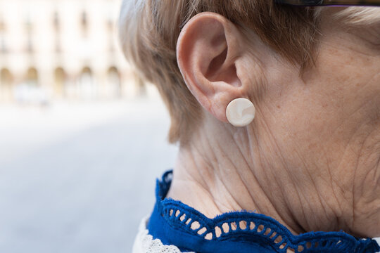 Closeup of an earring worn by a senior woman outdoors