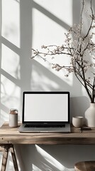 Laptop with blank screen on table against white wall. Mockup