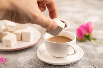 Coffee marshmallow with cup of coffee with hand on brown concrete. side view, selective focus