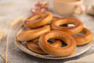 Homemade Ring Bagel with cup of coffee on brown concrete, side view, close up, selective focus.