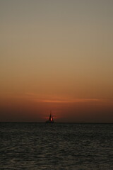 Beautiful sunset in Aruba with a sailboat in front of the sun that is going down