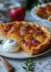 Tarte Tatin A Tarte Tatin with caramelized apples on a golden, flaky pastry crust. Served on a white plate with a dollop of whipped cream