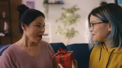 Biracial teenage girl surprising her mom with a gift, happy mother's day, family