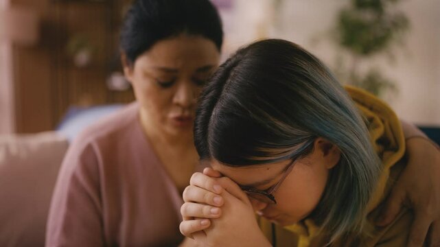 Caring Asian mother consoling and hugging her sad teenage girl, broken heart
