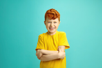 Capricious Red Haired Boy with Bared Teeth Looking to Camera, Clasping Hands in Front of him,...