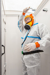 Asbestos surveyor with a ventilated mask and a protective Hazmat suit in a mobile decontamination...