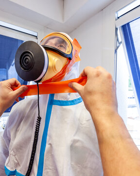 Asbestos surveyor receiving help to seal his ventilated mask and protective Hazmat suit, practical exercises during a training session about asbestos risk prevention