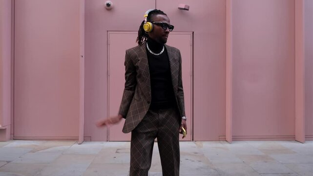 Stylish man putting on headphones and dancing