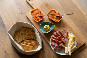 A delicious snack board is ready to be eaten. Simple but delicious with filet American, cheese, grilled sausage, mustard and some toast. Everything attractive on a wooden serving board.