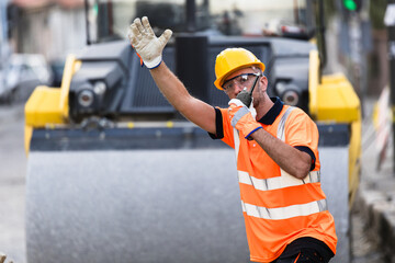 Construction worker directing traffic at a roadwork site during the day in an urban area