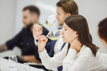 Sommeliers tasting various sorts of wine based smelling at the table indoors. 
