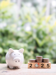 Piggy bank, Wooden block with number 2025 and stack of coins. The concept of saving money, Financial, Investment and Business growing in year 2025.