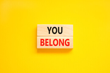 Belonging and you belong symbol. Concept words You belong on beautiful wooden blocks. Beautiful yellow background. Business belonging and you belong concept. Copy space.