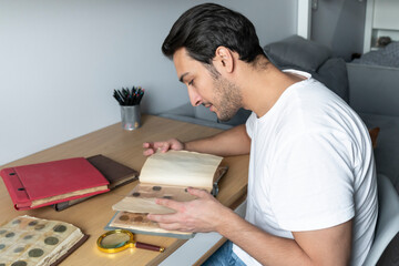 A passionate numismatist examines purchased old and ancient coins with a magnifying glass	
