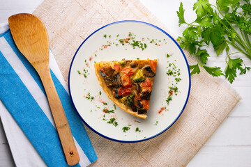 Piece of roasted vegetarian vegetable quiche. Top view table with decorations.